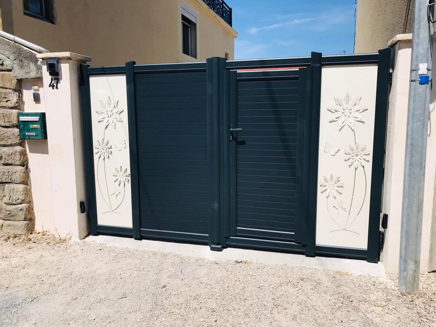 portail2 Photo d'un portail bicolore gris foncé et écru avec des motifs de fleurs et un portillon